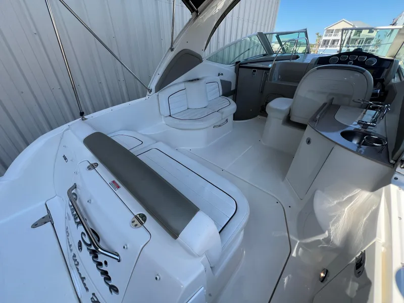 Slide: The Image of 2006 Sea Ray 290 Sundancer boat interior with seating and helm, docked near a building. - 6