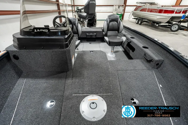 Slide: The Image of 2025 Lund 1675 Adventure SS boat interior with seating and steering console in a showroom. - 11