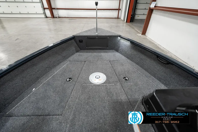 Slide: The Image of 2025 Lund 1675 Adventure SS boat interior with carpeted deck in a warehouse setting. - 16
