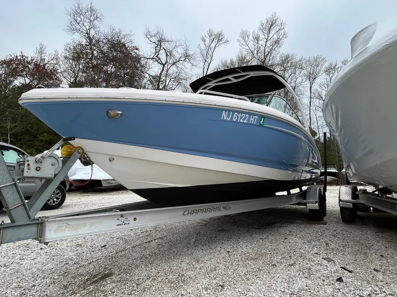 Slide: The Image of 2023 Chaparral 23 SSIOB boat on trailer, blue and white hull, parked outdoors. - 2