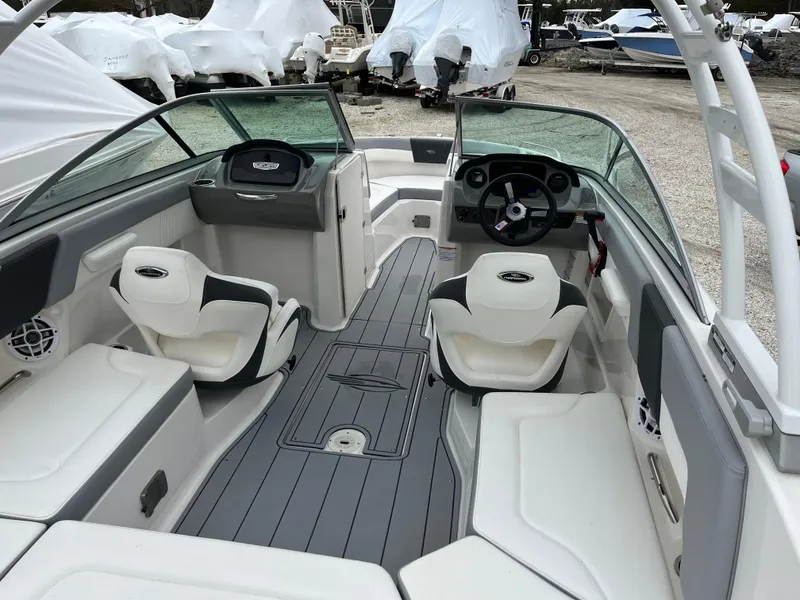Slide: The Image of 2023 Chaparral 23 SSIOB boat interior with seating and steering wheel, docked outdoors. - 9