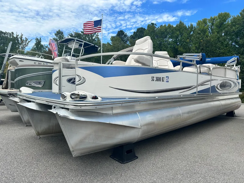 Slide: The Image of 2008 Manitou 24 Legacy pontoon boat with American flag, parked on a lot. - 0