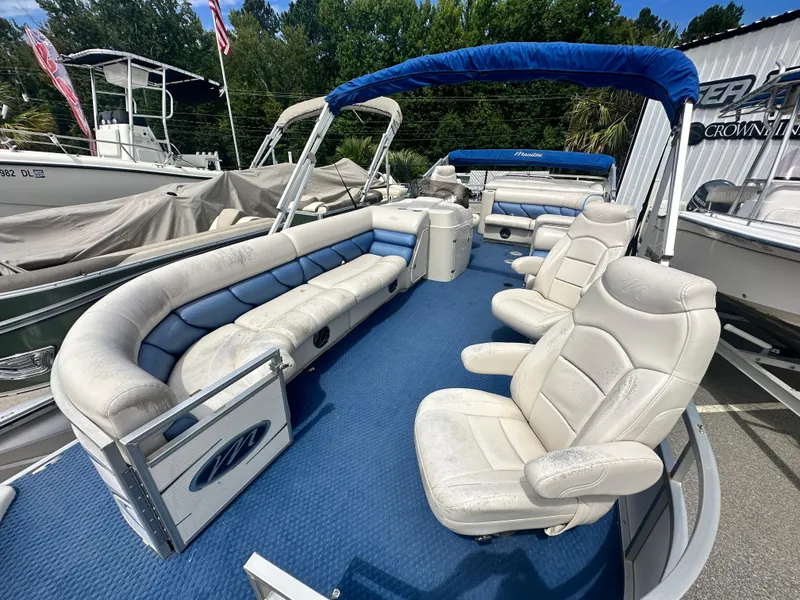 Slide: The Image of 2008 Manitou 24 Legacy pontoon boat with blue carpet and white seating, docked outdoors. - 1