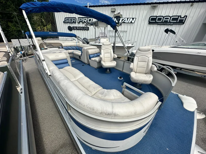 Slide: The Image of 2008 Manitou 24 Legacy pontoon boat with blue and white seating, docked at a marina. - 2