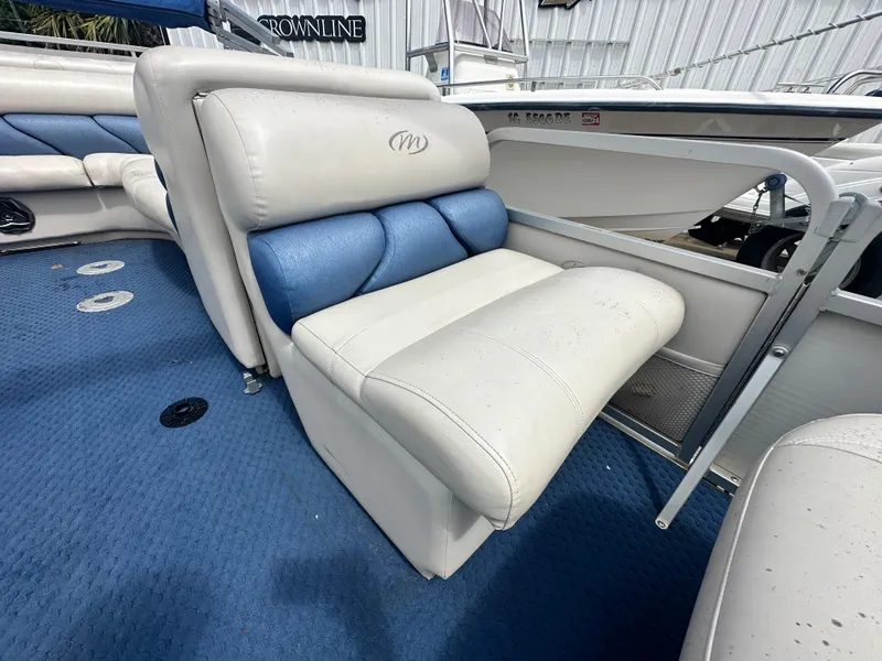 Slide: The Image of 2008 Manitou 24 Legacy boat interior with blue and white seating. - 5