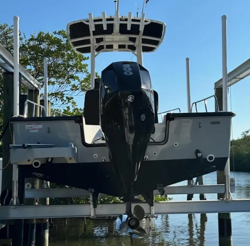 Slide: The Image of 2023 Boston Whaler 210 Montauk boat on lift, rear view, with outboard motor. - 2