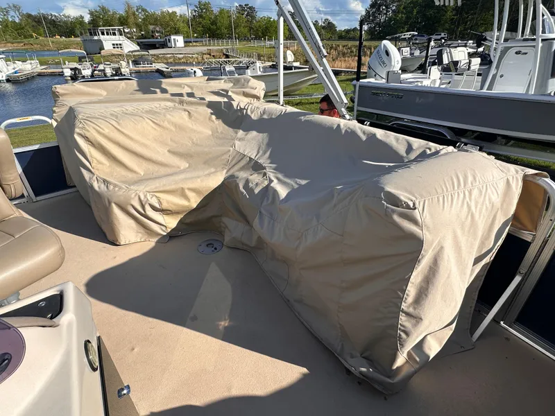 Slide: The Image of 2011 Avalon Windjammer 24' boat with covered seating, docked near other boats. - 2
