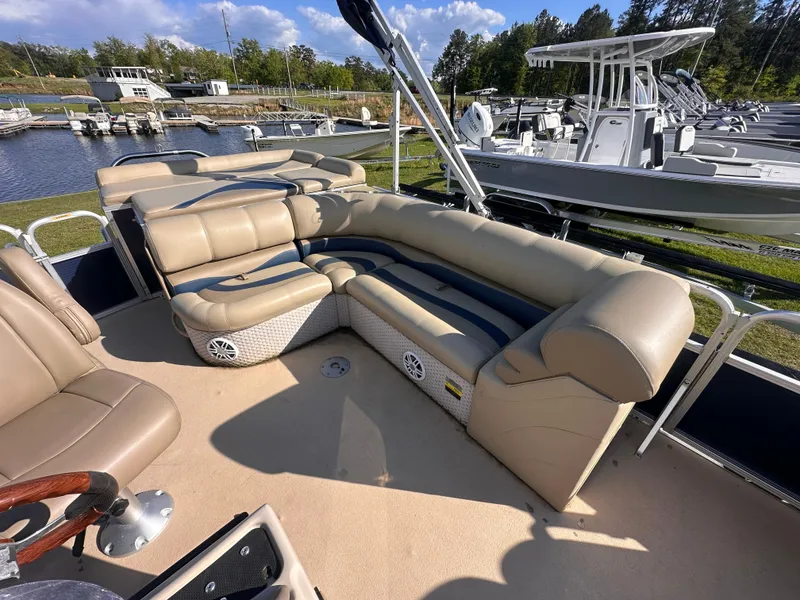 Slide: The Image of 2011 Avalon Windjammer 24' pontoon boat with beige seating, docked near other boats. - 7