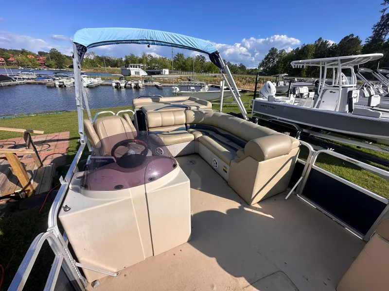 Slide: The Image of 2011 Avalon Windjammer 24' pontoon boat with seating, docked by a scenic marina. - 8