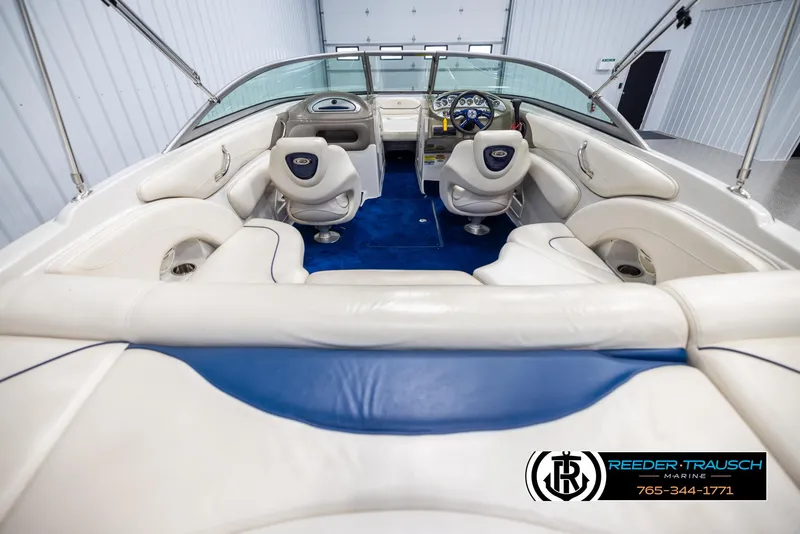 Slide: The Image of 2006 Crownline 230 LS boat interior with white seating and blue carpet in a showroom. - 13