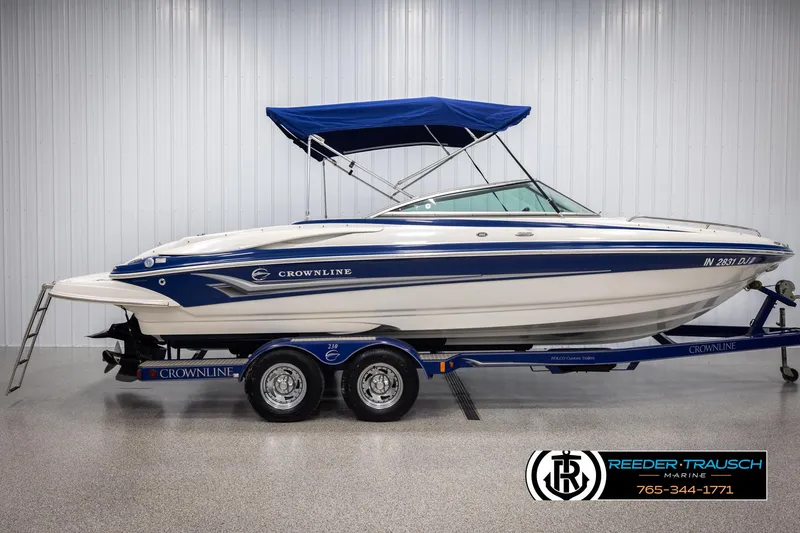 Slide: The Image of 2006 Crownline 230 LS boat with blue canopy on trailer in showroom. - 5