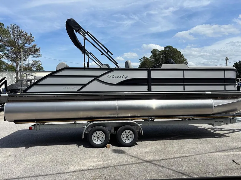 Slide: The Image of 2025 Bentley Pontoons Legacy QSB on trailer, sleek design, parked outdoors under blue sky. - 5