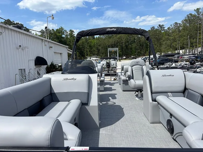 Slide: The Image of 2025 Bentley Pontoons Legacy QSB with luxurious seating, docked outdoors under a clear sky. - 8