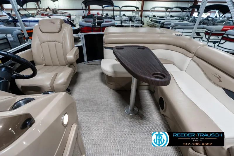 Slide: The Image of 2018 Bennington 20 SLMX pontoon boat interior with beige seating and wooden table. - 17