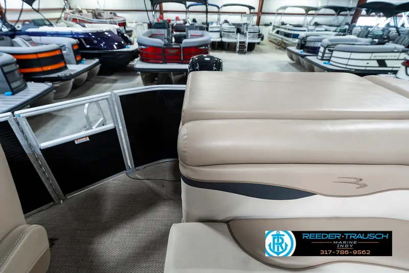 Slide: The Image of 2018 Bennington 20 SLMX pontoon boat interior in showroom with multiple boats displayed. - 18