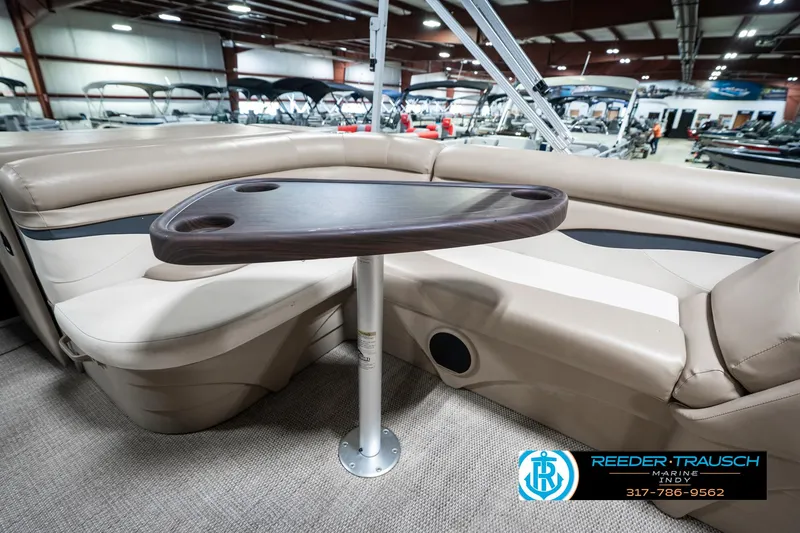 Slide: The Image of 2018 Bennington 20 SLMX boat interior with beige seating and a wooden table. - 26
