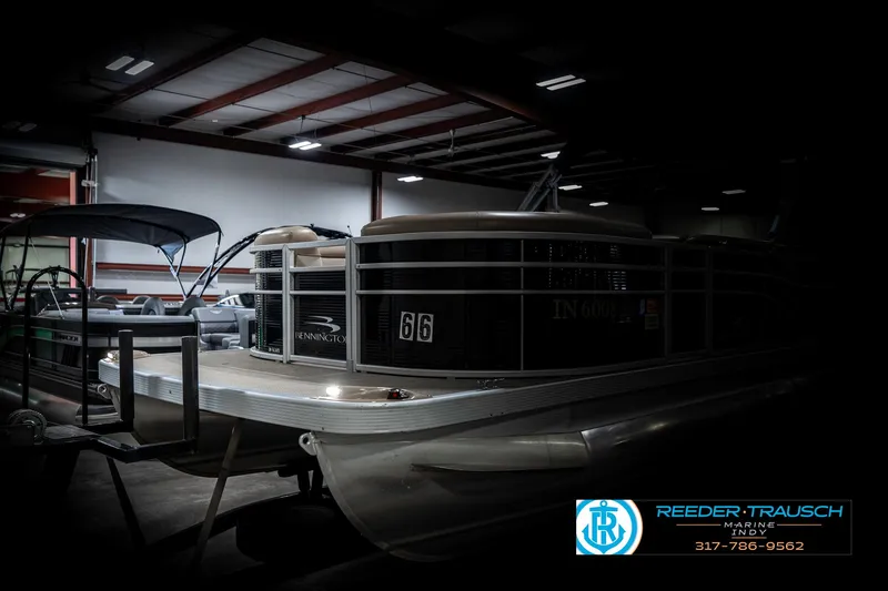 Slide: The Image of 2018 Bennington 20 SLMX pontoon boat in a dimly lit indoor storage facility. - 4