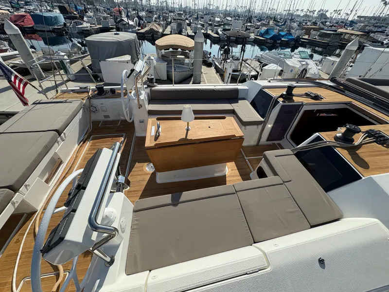 Slide: The Image of 2018 Dufour 560 Exclusive yacht deck with seating and table, docked in a marina. - 8