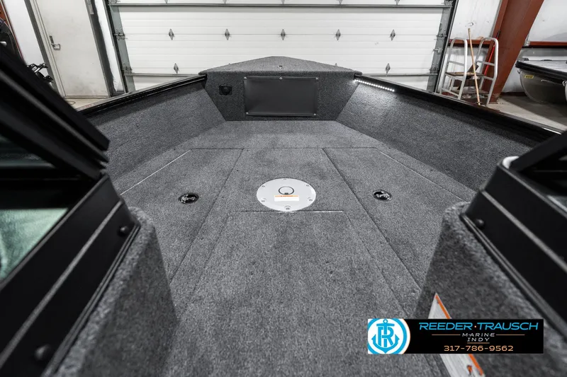 Slide: The Image of 2025 Lund 1775 Adventure Sport boat interior with gray carpeted deck in a garage. - 17