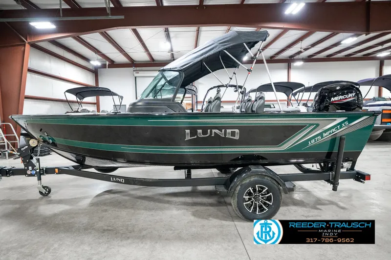 Slide: The Image of 2025 Lund 1875 Impact XS boat in a showroom, featuring a sleek design and modern amenities. - 11