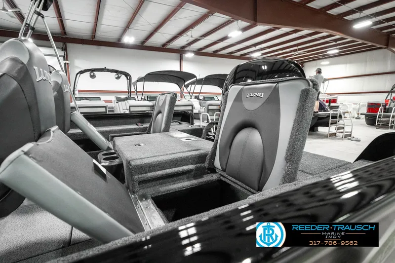 Slide: The Image of 2025 Lund 1875 Impact XS boat interior with seating and storage compartments in a showroom. - 27