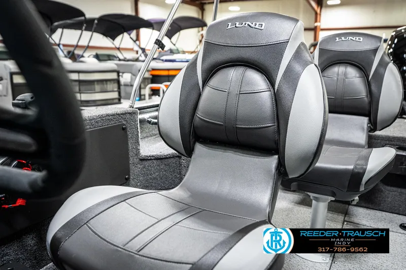 Slide: The Image of 2025 Lund 1875 Impact XS boat seats in showroom, featuring sleek black and gray design. - 44