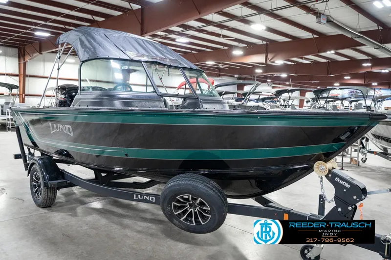 Slide: The Image of 2025 Lund 1875 Impact XS boat in showroom, black and green, on trailer. - 6