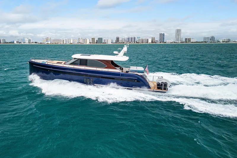 Slide: The Image of Steeler 60 S Performance yacht cruising on ocean with city skyline in background, 2021 model. - 12