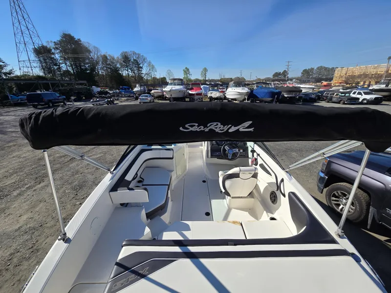 Slide: The Image of 2015 Sea Ray SPX 190 boat with canopy, parked in a lot with other vehicles. - 11