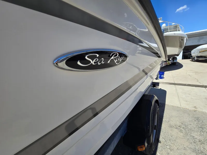 Slide: The Image of 2015 Sea Ray SPX 190 boat side view with logo, parked outdoors under blue sky. - 4