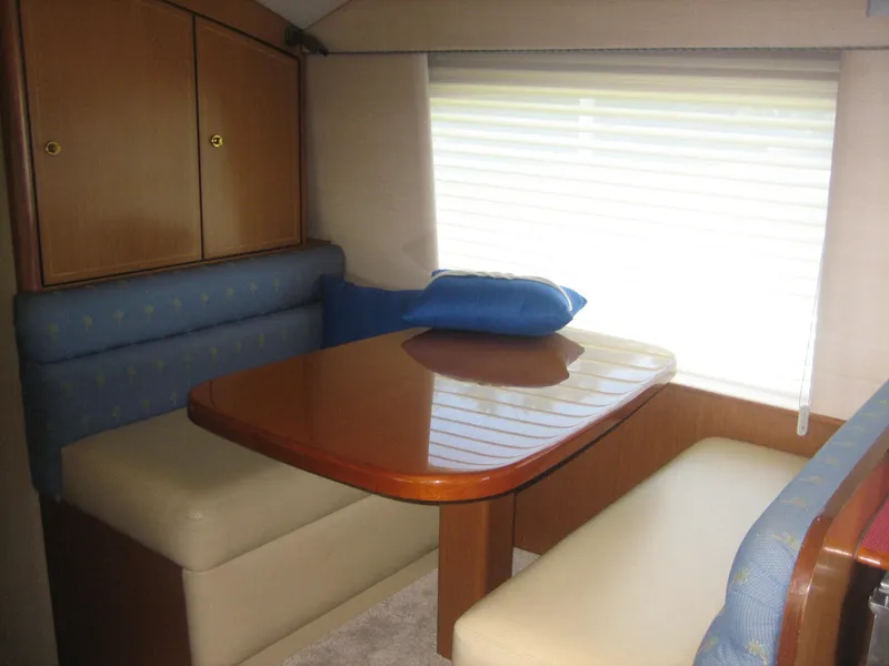 Slide: The Image of 2005 Ocean Yachts 50 Super Sport interior dining area with wooden table and cushioned seating. - 6