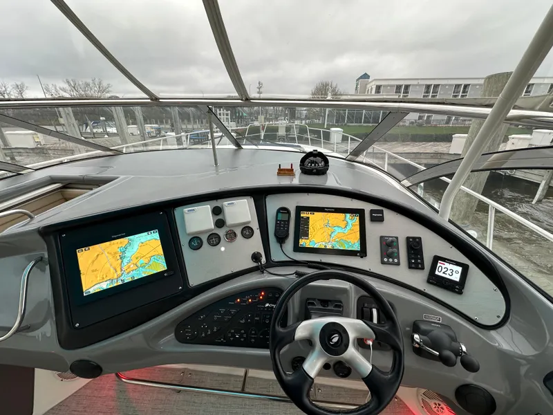 Slide: The Image of 2005 Cruisers Yachts 540 Express helm with navigation screens and steering wheel. - 13