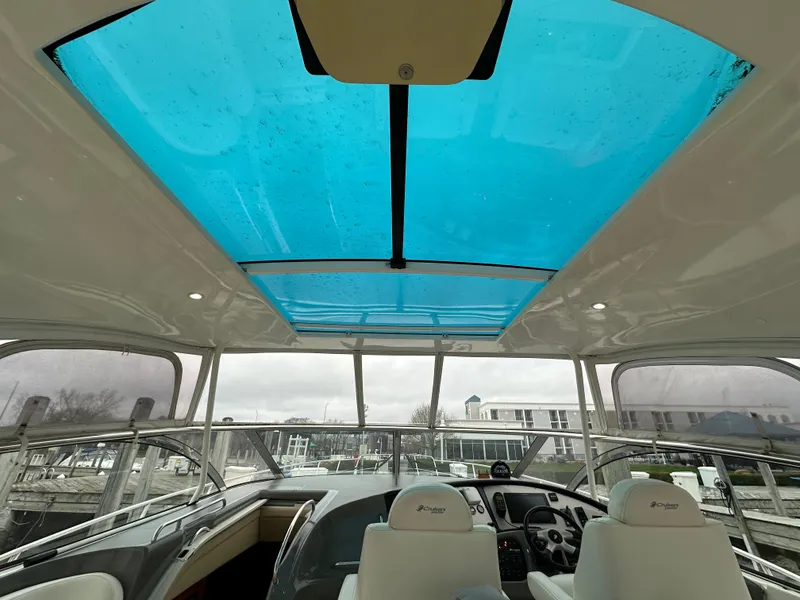 Slide: The Image of 2005 Cruisers Yachts 540 Express helm with blue-tinted sunroof and modern controls. - 16