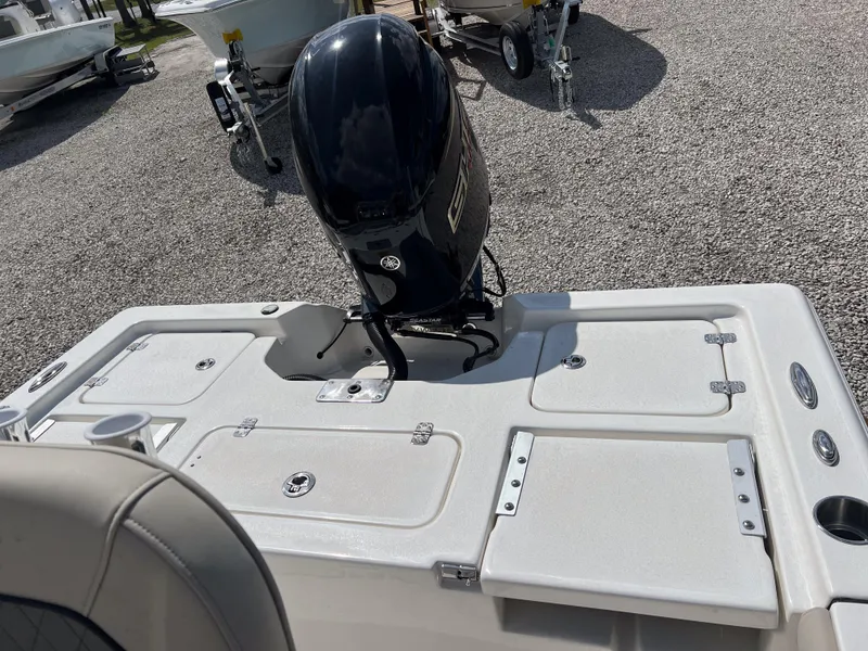 Slide: The Image of 2025 Key West 210 Bay Reef boat with outboard motor, parked on gravel. - 16