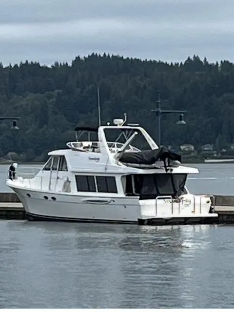 The Image of 2005 Meridian PILOTHOUSE yacht docked by a scenic forested shoreline. - 0