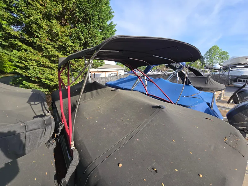 Slide: The Image of 2015 Bennington 24 SSRX30 boat with canopy, parked outdoors under clear sky. - 38