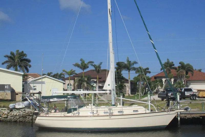 The Image of 1999 Island Packet 380 sailboat docked near palm trees and houses. - 0