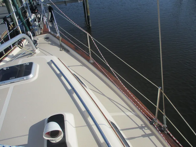 Slide: The Image of 1999 Island Packet 380 sailboat deck with rigging, docked by calm waters. - 11