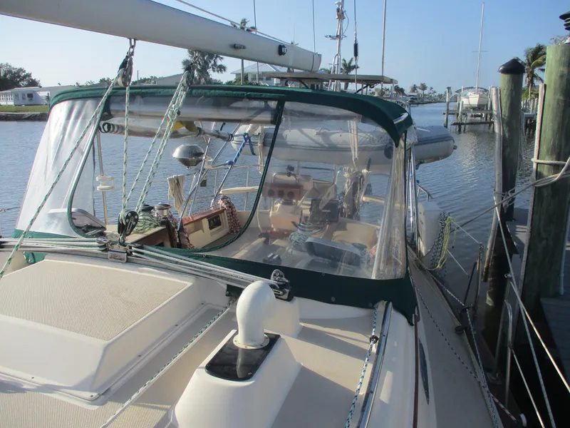 Slide: The Image of 1999 Island Packet 380 sailboat docked, featuring a green canopy and spacious deck. - 14