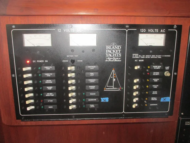Slide: The Image of Electrical control panel of a 1999 Island Packet 380 yacht, featuring voltage meters and switches. - 44