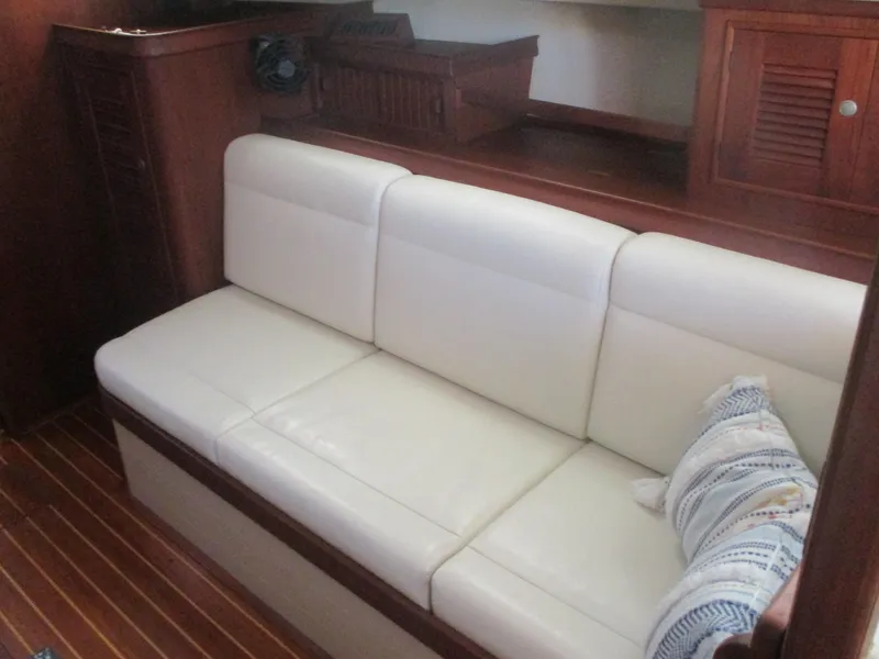 Slide: The Image of White leather sofa in 1999 Island Packet 380 yacht interior, with wooden cabinetry and striped pillow. - 48