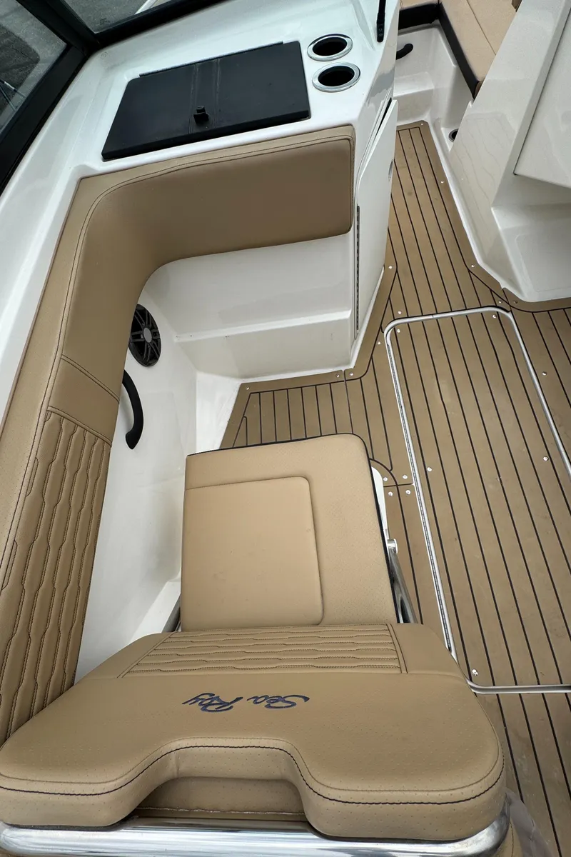 Slide: The Image of 2022 Sea Ray SPX 210 OB boat interior with tan seating and wood-style flooring. - 16