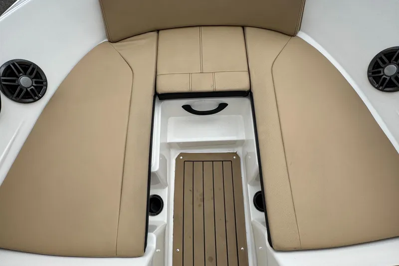 Slide: The Image of 2022 Sea Ray SPX 210 OB boat interior with tan cushioned seating and wood-style flooring. - 19