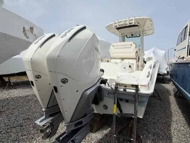 Slide: The Image of 2023 Boston Whaler 280 Dauntless boat with dual outboard engines, docked on gravel. - 14