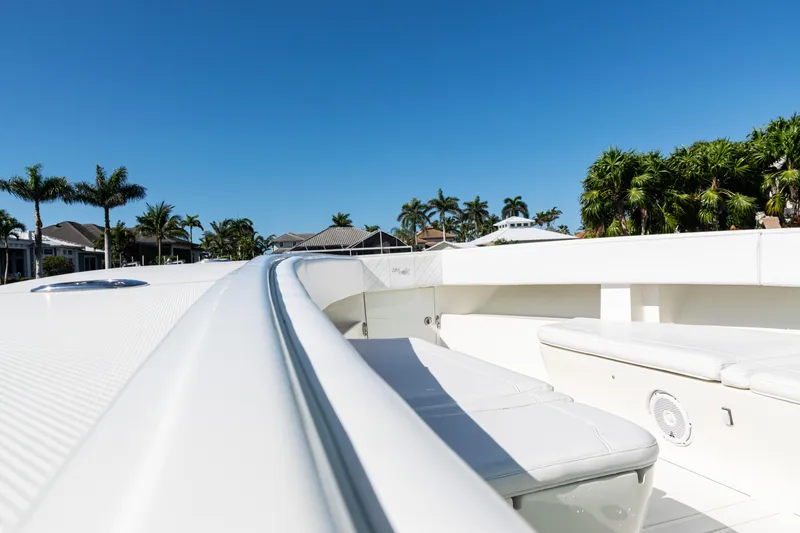 Slide: The Image of 2015 SeaVee 390Z boat deck with seating, surrounded by palm trees and clear blue sky. - 12