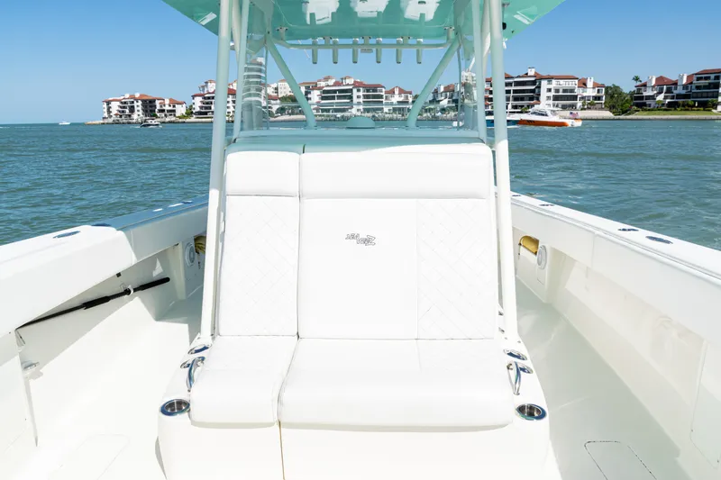 Slide: The Image of 2015 SeaVee 390Z boat interior with white seating, ocean view, and coastal buildings. - 21