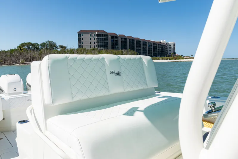 Slide: The Image of 2015 SeaVee 390Z boat interior with white seating, coastal view, and modern buildings in the background. - 29