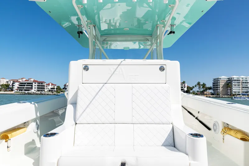 Slide: The Image of 2015 SeaVee 390Z boat interior with white seating and turquoise canopy, docked near waterfront buildings. - 30