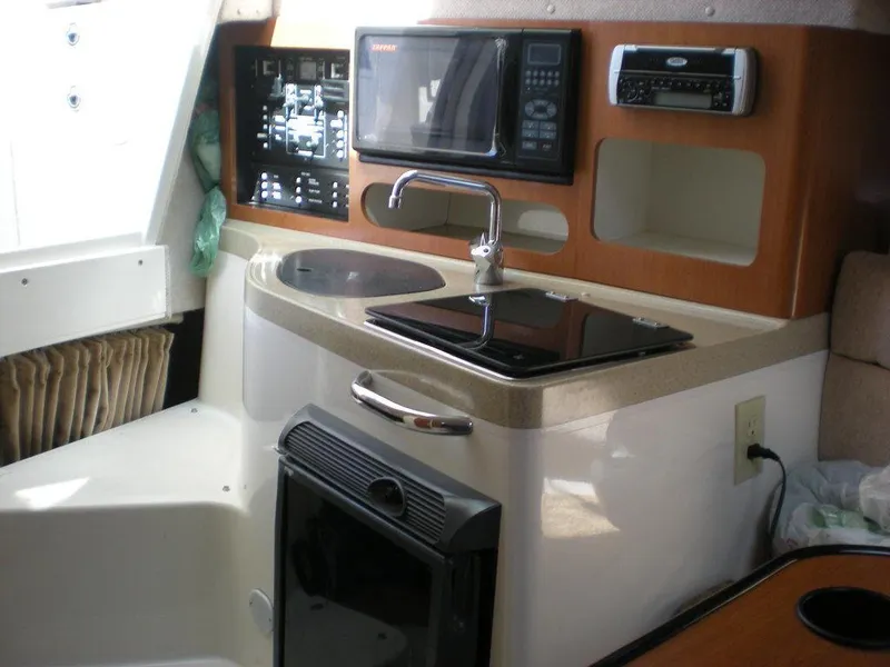 Slide: The Image of 2006 Seaswirl Striper boat interior with kitchenette, featuring sink, stove, and microwave. - 16