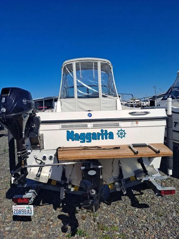 Slide: The Image of 1998 Bayliner 2052 boat named "Maggarita" with outboard motor, parked on gravel. - 6